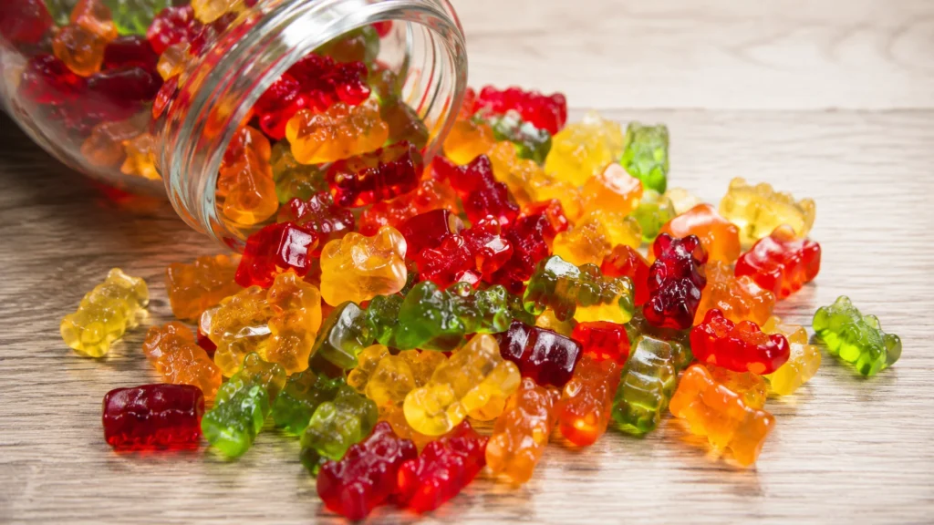 A pile of colorful translucent gummy bears spilling from a glass jar