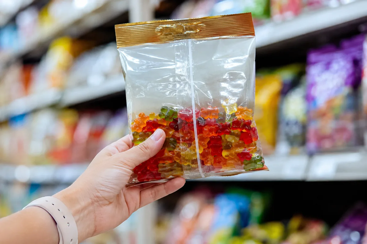 Reading a Candy Label A hand holding a bag of gummy bears up to check the allergen panel